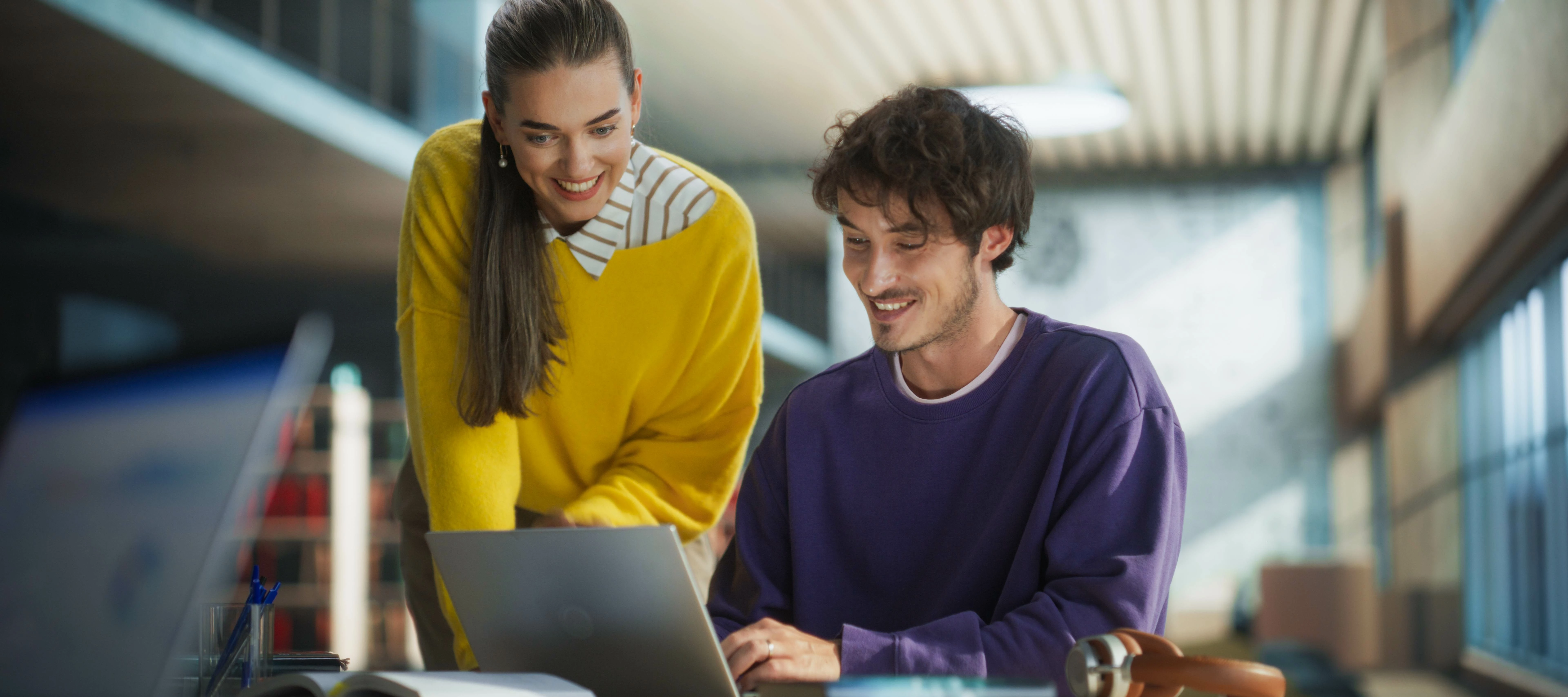 two people smiling and working on a laptop
