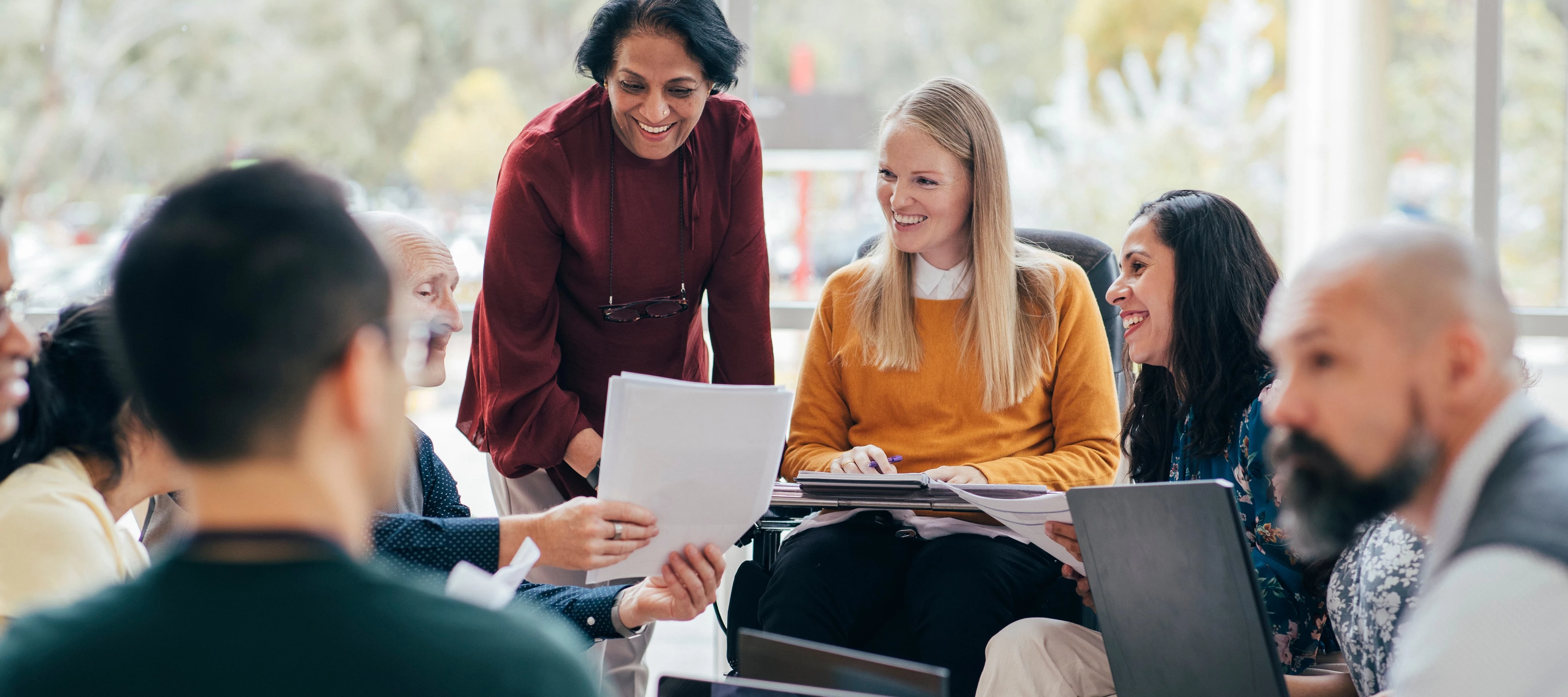 employees with laptops and smiling while looking at paperwork and results