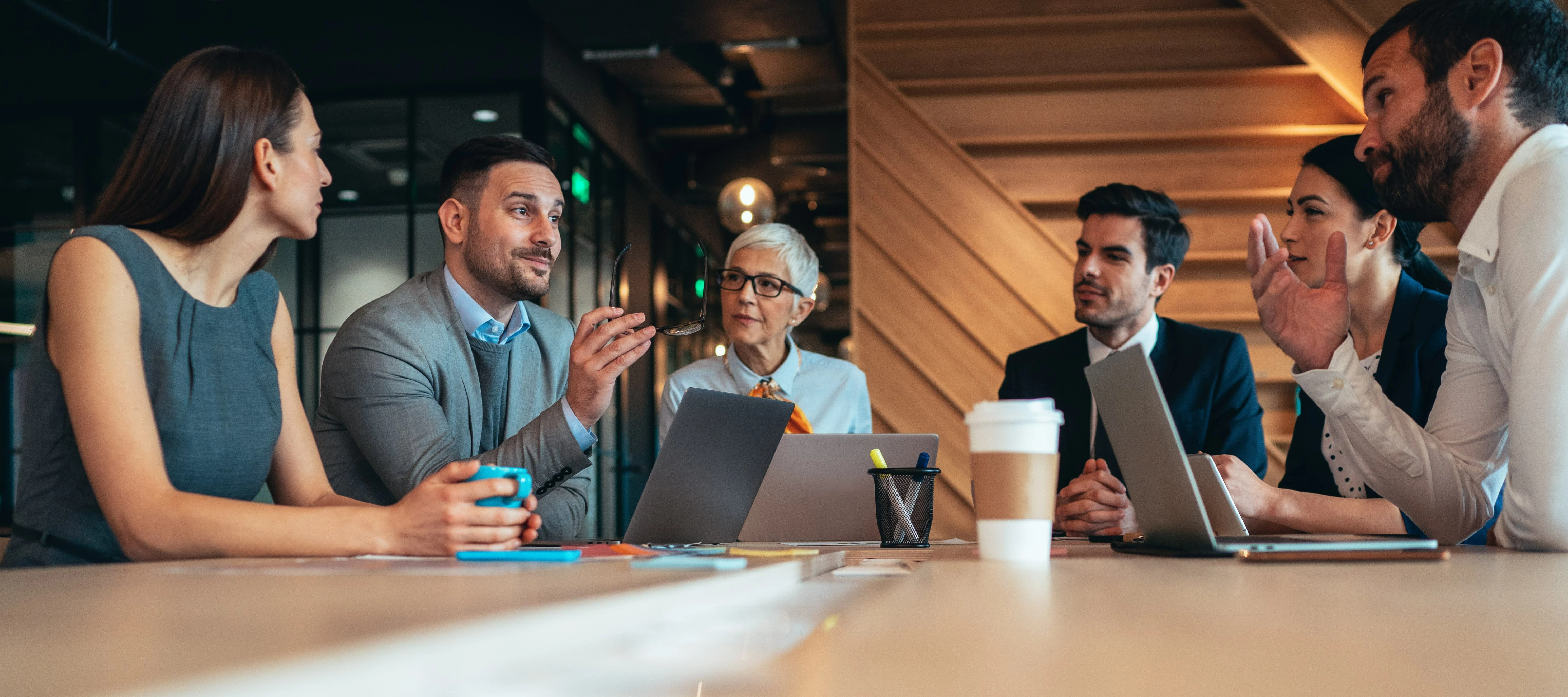 Group of employees in business meeting with laptops and coffee
