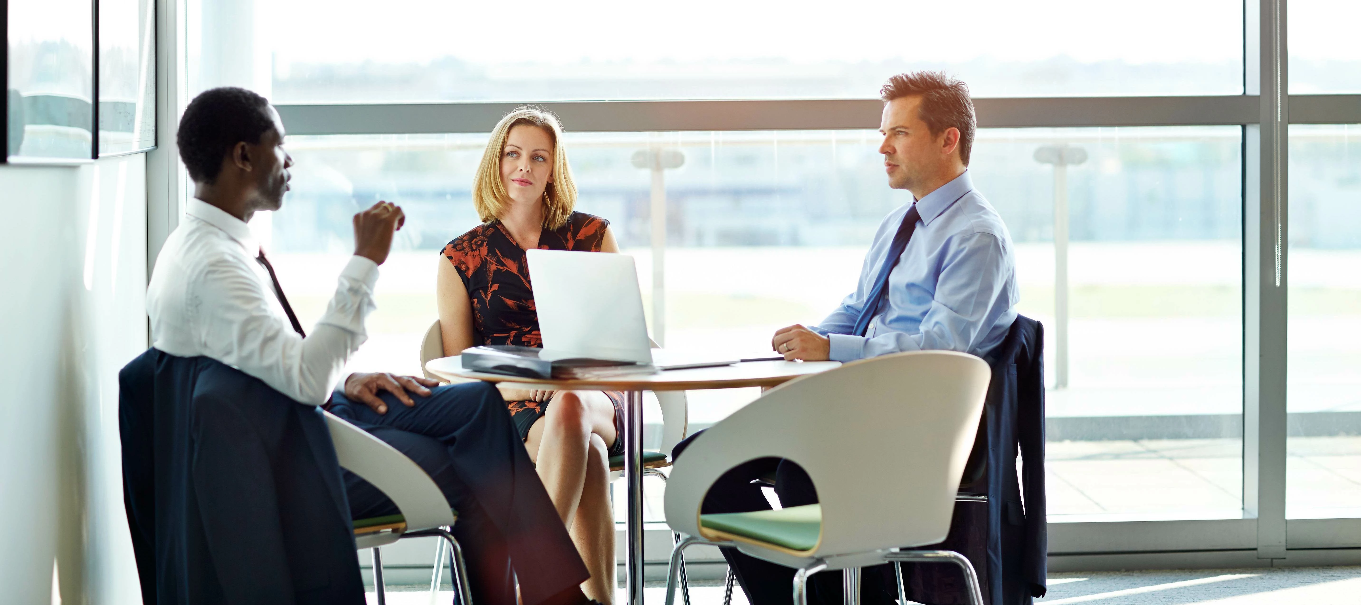 business meeting with executives sitting at a table with a laptop