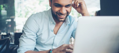 man smiling while working on his laptop