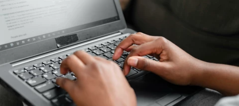person typing on laptop to AI agent, hands only showing