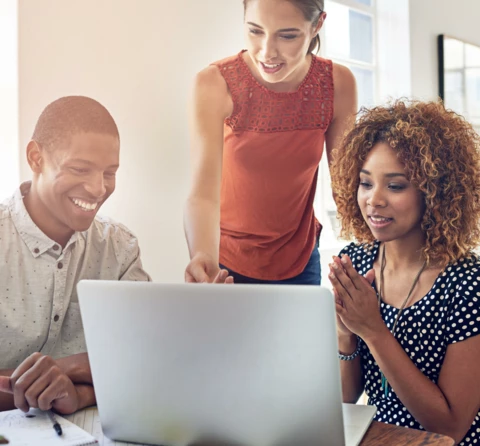 Three people looking at a laptop and smiling