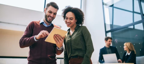 two people looking at a tablet and smiling