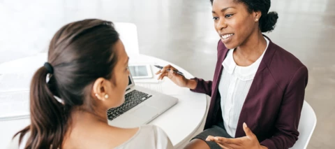 two people discussing services at a table with a laptop