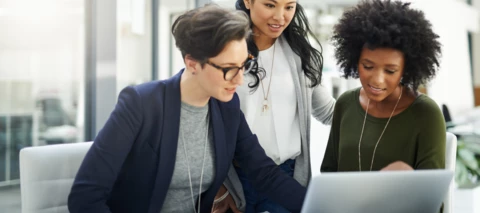 three women reviewing information on a laptop