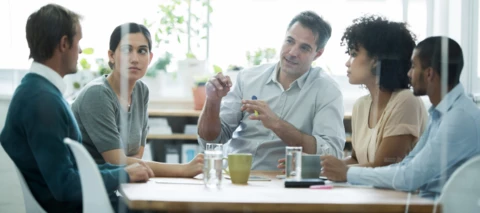 people sitting at a table with coffee and paperwork having a discussion