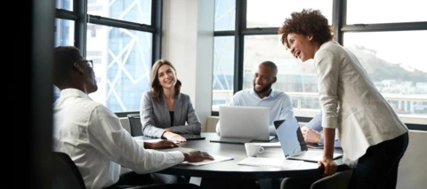 business meeting with coworkers and laptops on the table smiling